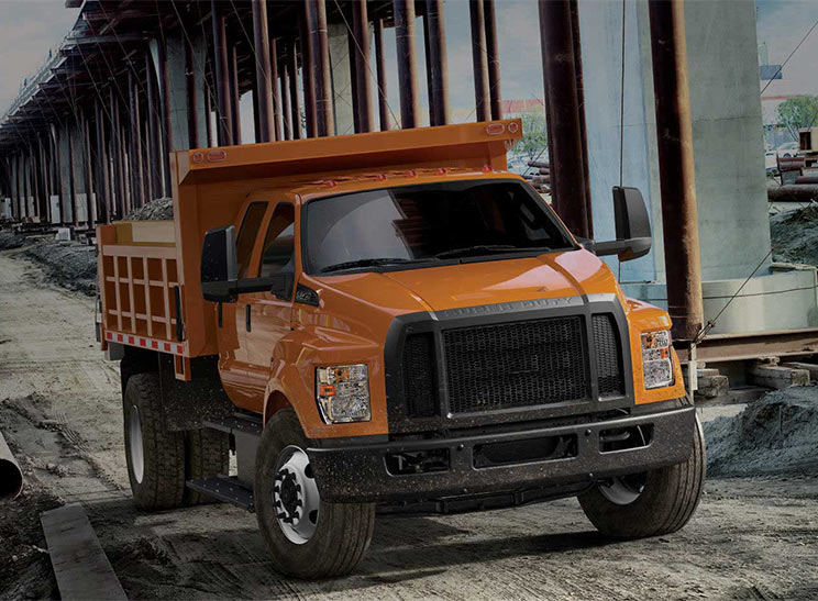 Commercial Vehicles. Image of orange dump truck.