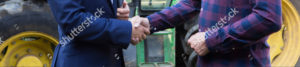 stock-photo-farmer-and-businessman-shaking-hands-with-tractor-in-background-489088585-cropped
